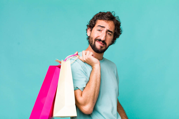 young adult hispanic crazy man. shopping bags concept - Foto, imagen