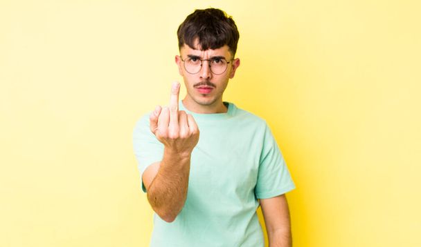 young adult hispanic man feeling angry, annoyed, rebellious and aggressive, flipping the middle finger, fighting back - Foto, Bild