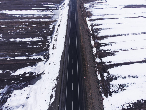 Aerial top view of a road with one lane and snow in winter. - Foto, Imagem