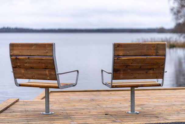 Металл с деревянным покрытием современные стулья в зоне отдыха перед озером - Фото, изображение