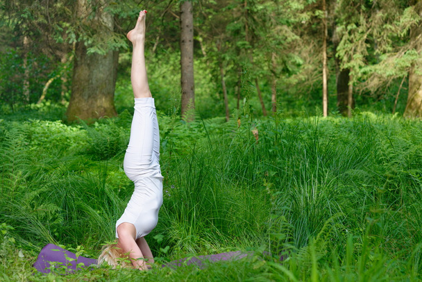vrouw praktijken yoga in de natuur - Foto, afbeelding