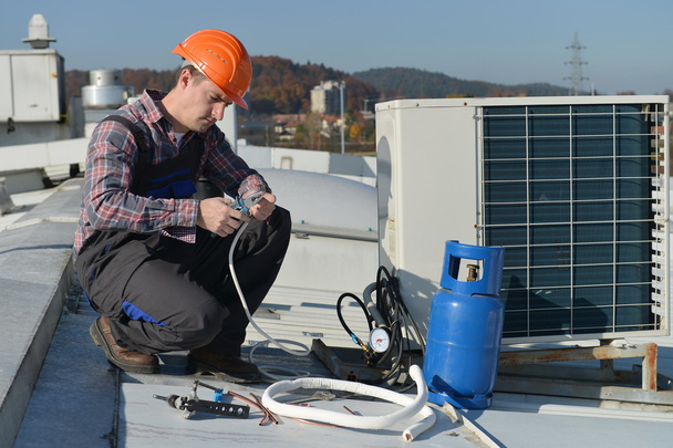 Giovane riparatore sul tetto sistema di fissaggio aria condizionata
 - Foto, immagini