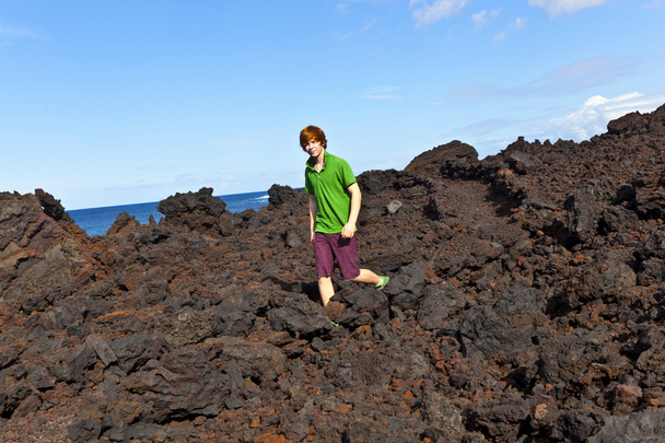 Poika kävelee vulkaanisella alueella
 - Valokuva, kuva