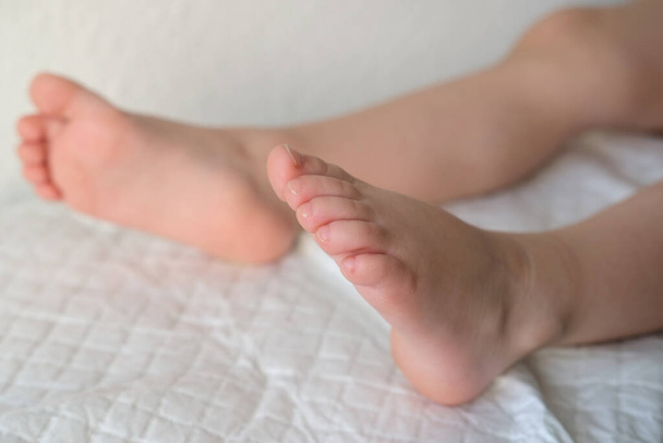 クローズアップ赤ちゃんの素足、女性の手は優しく子供の足をこね、治療を行い、予防マッサージを行い、筋骨格系を強化し、身体的発達を刺激し、平らな足の予防 - 写真・画像