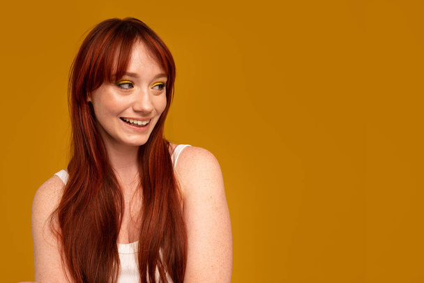 Authentic cheerful ginger girl with beautiful smile, natural freckles, long hair and fringe. Attractive red head woman posing in studio. A lot of copy space. - Φωτογραφία, εικόνα