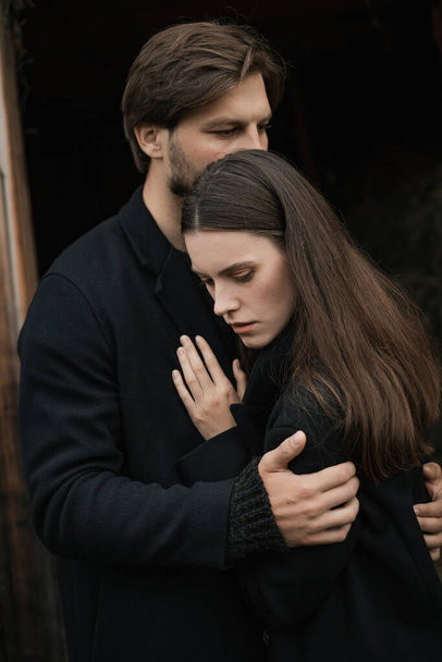 A young couple in love in black coats walks in the countryside in the rain. Autumn gloomy mood. cinematic image - Photo, Image