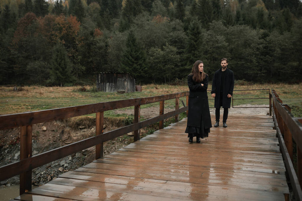A young couple in love in black coats walks in the countryside in the rain. Autumn gloomy mood. cinematic image - Fotografie, Obrázek