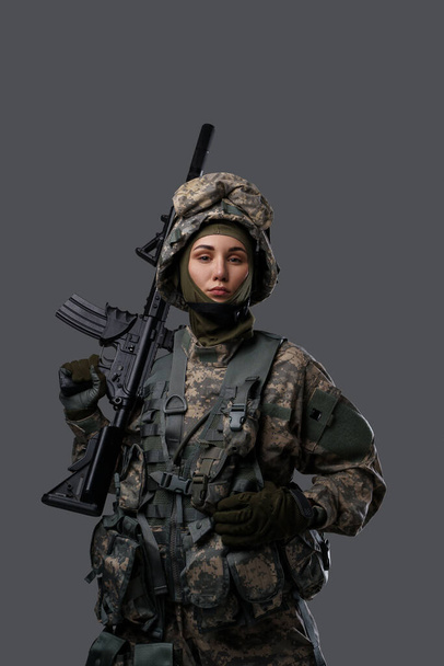 Soldado feminino olhando para a câmera contra fundo cinza - Foto, Imagem