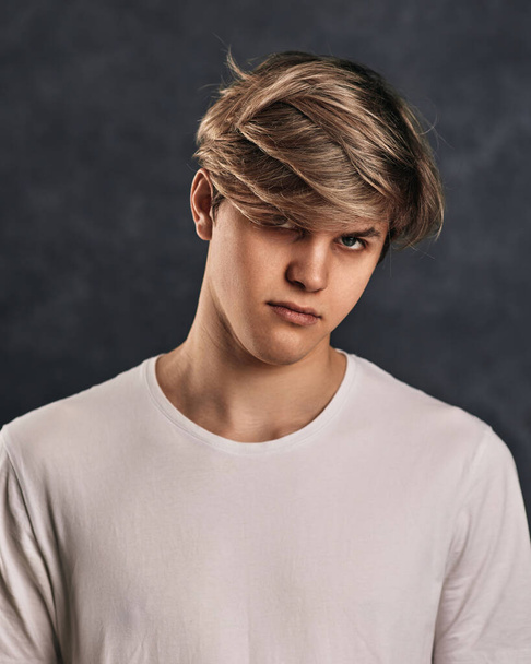 upset young guy in t-shirt on gray background. - Valokuva, kuva