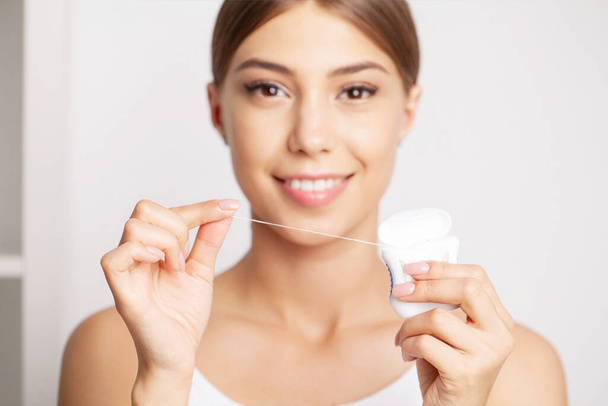Cleaning teeth with dental floss, perfect healthy tooth - Foto, immagini