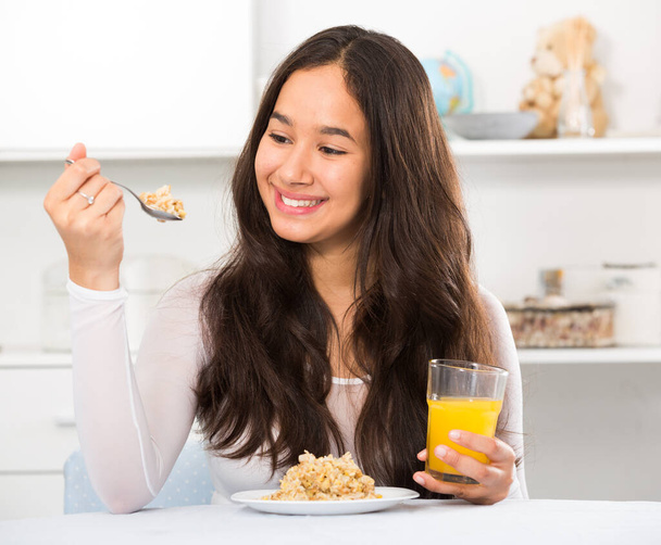 усміхнена дівчина їсть зернові та п'є сік
 - Фото, зображення