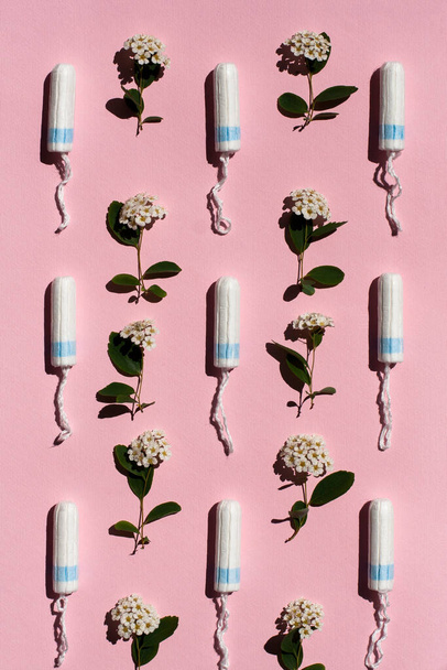 Медичний жіночий тампон і білі квіти на рожевому тлі. Гігієнічний білий тампон для жінок. Бавовняний тампон. Менструація, ліки
. - Фото, зображення