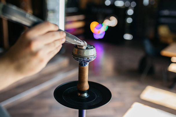 Hookah smoking at a party concept. Hookah stands on a wooden table in the interior of the restaurant. Smoking concept. Traditional hookah, spark, hookah sparks. Hookah on the table. - 写真・画像
