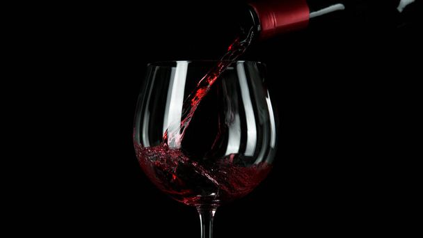 Close-up of pouring red wine into glass. Isolated on black background. - Foto, imagen