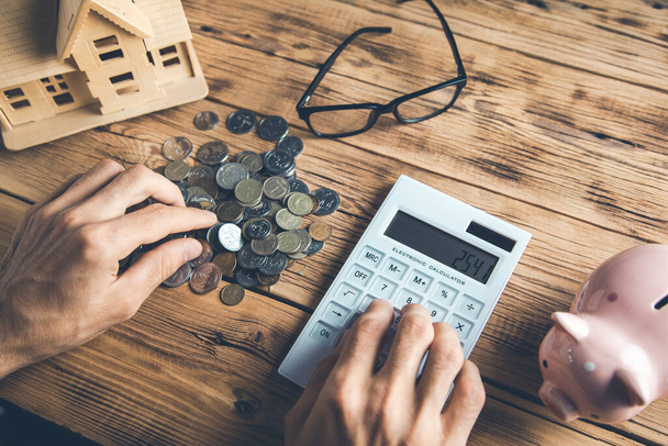 hombre mano dinero con calculadora y modelo de casa en el escritorio - Foto, Imagen