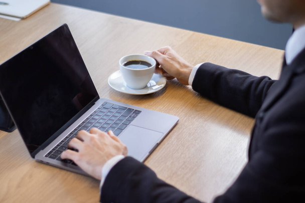 üzletember fekete öltönyben dolgozik az íróasztalnál laptop az irodában - Fotó, kép
