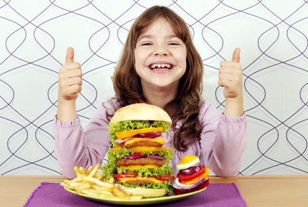 onnellinen pieni tyttö iso hampurilainen ja peukut pystyyn
 - Valokuva, kuva