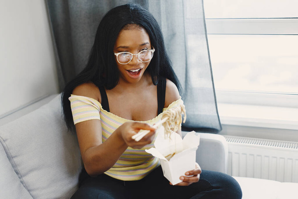 美しい若いアフリカ系アメリカ人女性が麺を食べる - 写真・画像