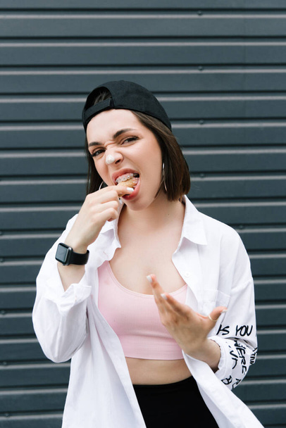 Brunette girl in a cap and shirt eats fun ice cream - Photo, image