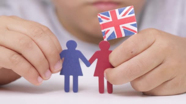 Les femmes de papier dans les mains d'un garçon avec le drapeau britannique. - Séquence, vidéo