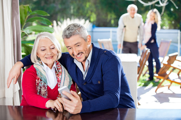 Усміхнений онук та бабуся використовують смартфон
 - Фото, зображення