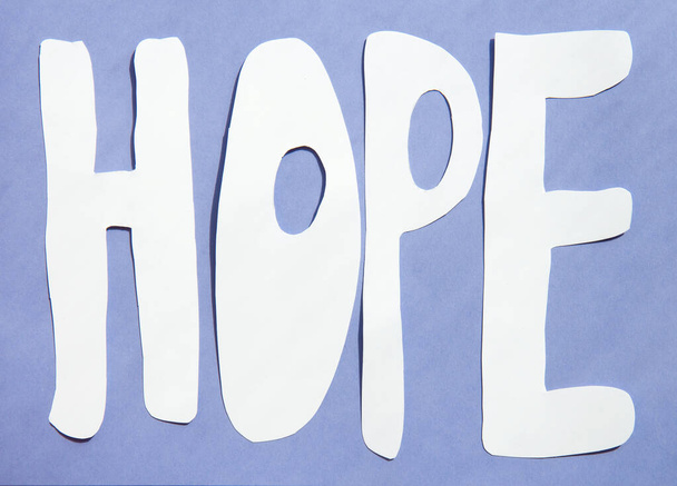 Χάρτινη τέχνη Λέξη Ελπίδα σε ένα φωτεινό βιολετί φόντο με αντιθέσεις σκιές - Φωτογραφία, εικόνα