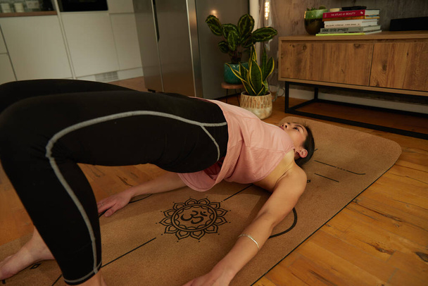 Young beautiful woman exercising on yoga mat in the room - Foto, imagen