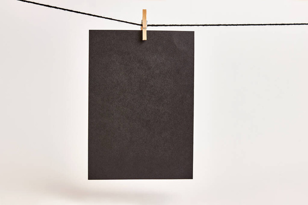 Sheets of black paper hung with clothespins on a rope on a white background. Black background for inscriptions or advertising images. - Foto, immagini