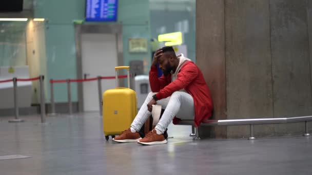 Вымотанный африканский мужчина на длинной ночной связи в аэропорту, ждет самолет, сидящий в терминале - Кадры, видео