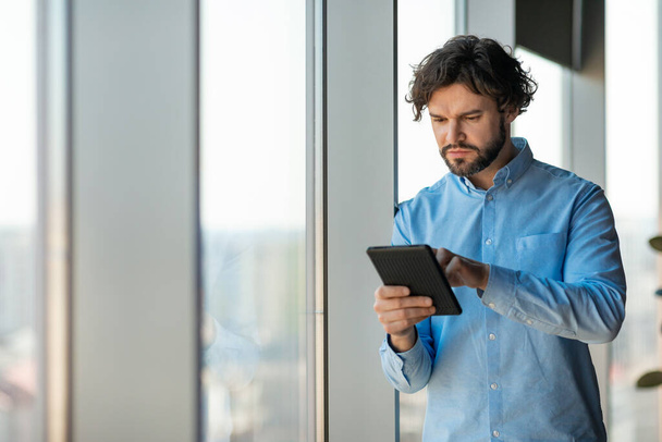 Portrait d'un homme concentré utilisant une tablette numérique au bureau - Photo, image