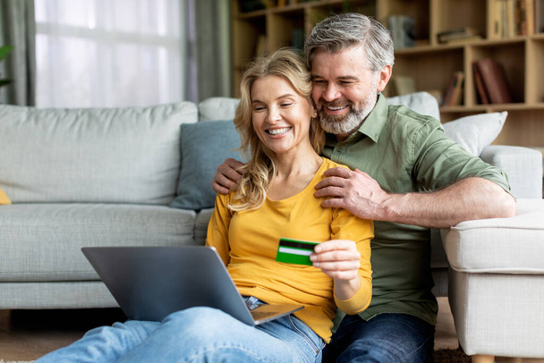 Εύκολες πληρωμές. Μεσήλικες σύζυγοι που ψωνίζουν online με φορητό υπολογιστή και πιστωτική κάρτα - Φωτογραφία, εικόνα