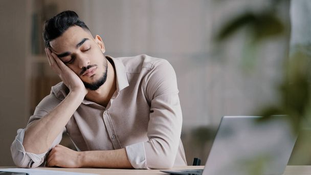 senny zmęczony latynoski człowiek pracownik mężczyzna biznesmen marzyciel śpi w domu biuro drzemka jest odpoczynek arabski leniwy student przytłoczony niezdrowy facet uczucie wyczerpany po ciężkiej pracy komputera - Zdjęcie, obraz