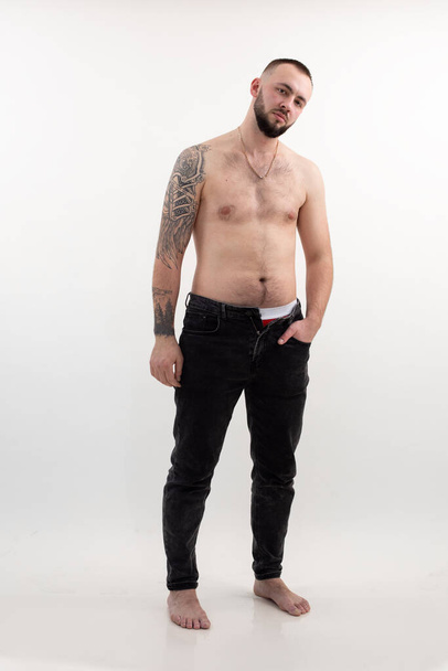Confident tattooed brutal man with beard and tattoo, shirtless and topless, on whit background. Naked self acceptance - Fotó, kép
