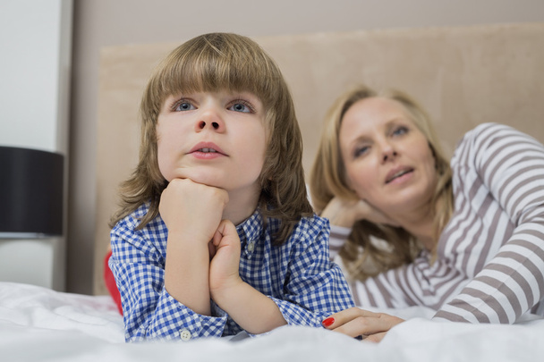 boy and mother lying on bed - Photo, image