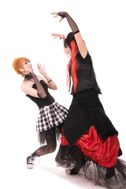 Piękna młoda dziewczyna z czerwonymi włosami, nosząca długą gotycką czarno-czerwoną koronkową suknię flamenco z czarnym gorsetem. klęcząc na ziemi. izolowany na białym tle. - Zdjęcie, obraz