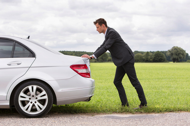 Businessman pushing broken down car - Photo, Image