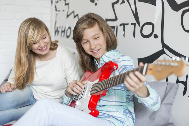 Tyttö kuuntelee sisko soittaa kitaraa
 - Valokuva, kuva