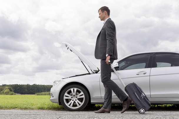 businessman with suitcase leaving broken down car - Zdjęcie, obraz