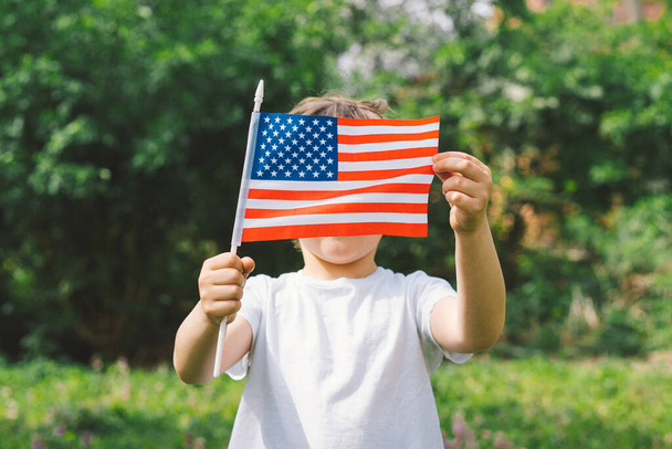 Happy little patriotic boy holding American flag. - Zdjęcie, obraz
