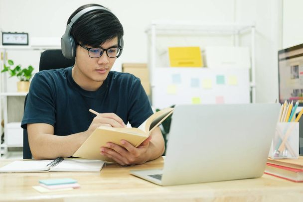 Молодой человек учится перед ноутбуком дома - Фото, изображение