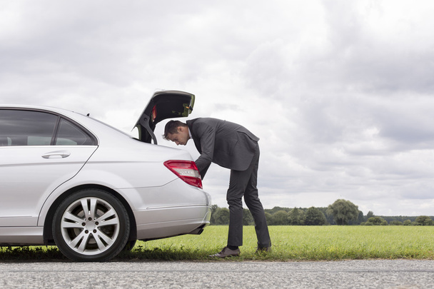 Businessman looking in trunk of car - Zdjęcie, obraz