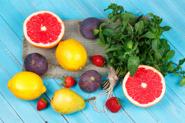 Grapefruits, pears, lemons, figs, strawberry, pomelo and mint on wooden background. Still life with fruits - Foto, Imagem