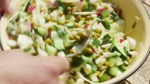  Az ember keze egy kanállal megkeveri a salátát konzerv borsóval.. - Felvétel, videó