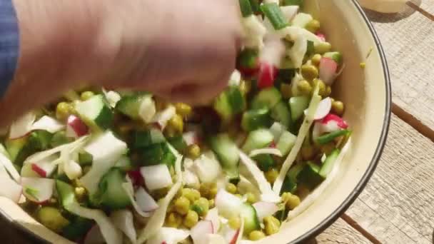  mensenhand met een lepel mengt lentesalade met erwten in blik. - Video