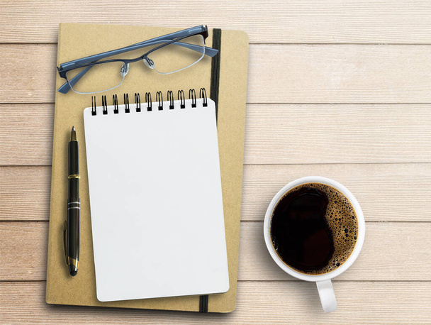 Bloco de notas em branco, óculos, caneta e xícara de café no fundo da mesa do escritório. Vista superior com espaço de cópia. - Foto, Imagem