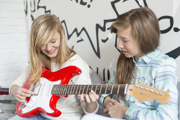 Girl listening to sister playing guitar - Foto, afbeelding