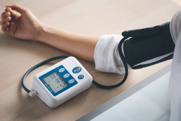 self blood pressure and heart rate measurement with blood pressure monitor machine, healthcare and medical concept - Foto, Imagen
