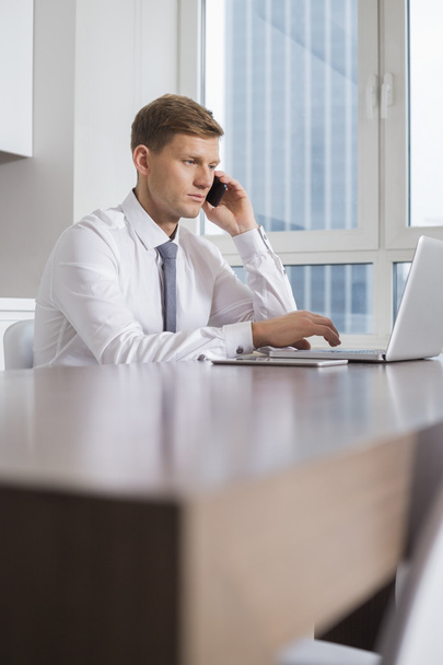 businessman on call while using laptop - Fotó, kép