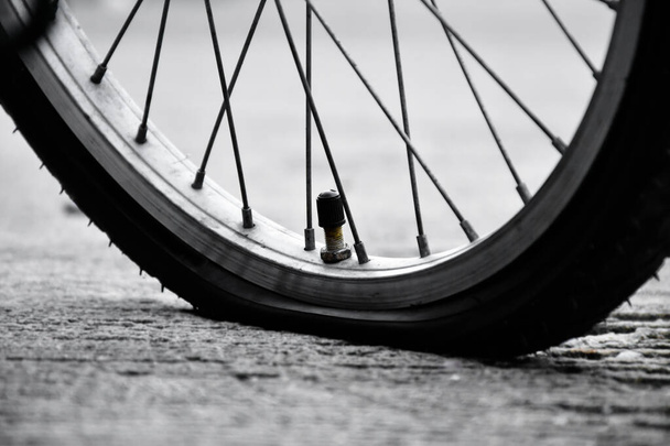 Vista de perto do pneu traseiro da bicicleta vintage que é plana e estacionada no pavimento perto da estrada rural. - Foto, Imagem