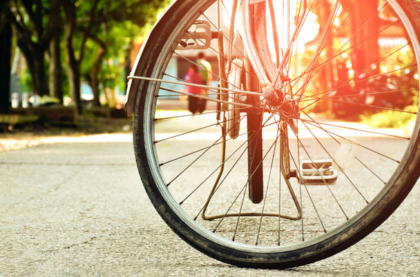 Etunäkymä vintage-pyörän eturenkaaseen, joka on pysäköity kapealle kadulle julkisessa puistossa, pehmeä ja valikoiva keskittyminen, vintage-pyöräkonsepti. - Valokuva, kuva